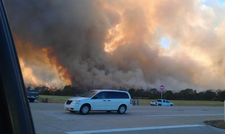 Cars stopped in front of the rising smoke.